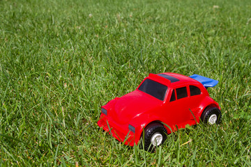 The toy red car in field of green grass. Background for your concept.