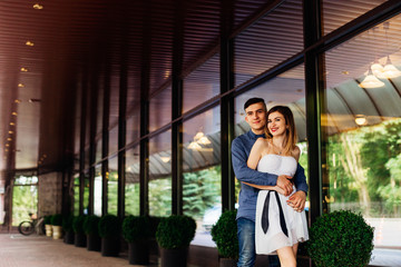 Young couple stands hugging before the modern glass building