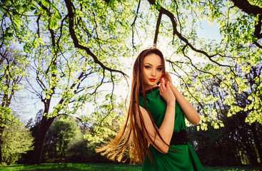 Stunning woman whirls her hair while standing under large branch