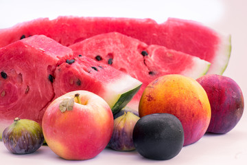 Assorted fruits, slices of watermelon, peach, fig, plum, apple. On a white background