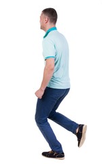 Fototapeta premium Back view of running man in blue polo. Walking guy in motion. Rear view people collection. Backside view of person. Isolated over white background.