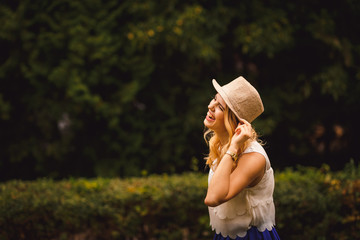 Laughing girl in beige hat walks in the park