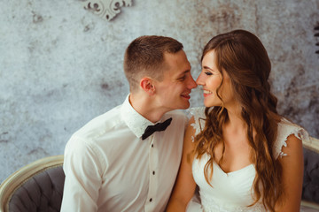 Attractive young couple sits smiling on the old-fashioned grey c