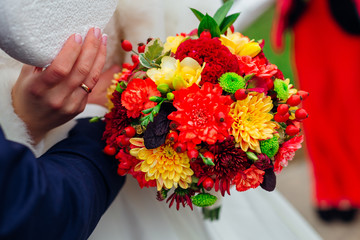 Closeup of autumn wedding bouquet helf by a bride