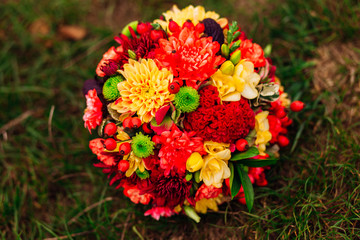Wedding bouquet made of red, yellow and green autumn flowers lie
