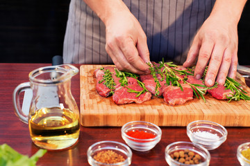 Fresh raw beef meat. Men seasons meat with oil, herbs and spice