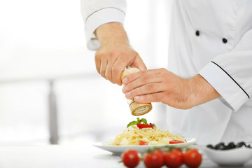 Chef preparing delicious pasta in kitchen