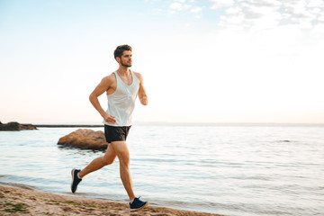 Handsome man athlete running at the beach