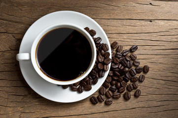 still life photography : coffee in white coffee cup and coffee beans on old wood