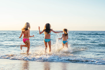 Fototapeta na wymiar three girls having fun on beach, friends on beach in sunset light