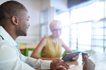 Obraz premium Two creative millenial small business owners working on social media strategy using a digital tablet while sitting at desk