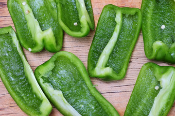 Fresh green bell pepper slices on wooden desk background