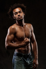 Fototapeta na wymiar Young sportive african man posing over black background.