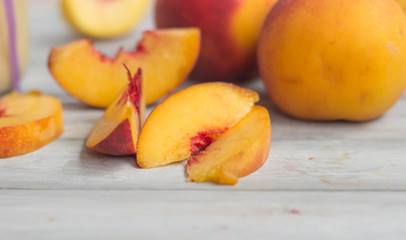 Peaches, whole and slices, on white wooden tabletop