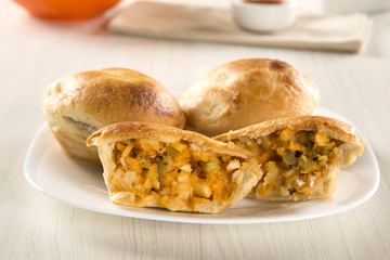Empada Brazilian snack. pie with palm on white plate on wooden b