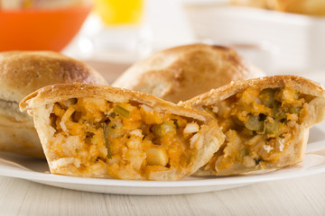 Empada Brazilian snack. pie with palm on white plate on wooden b