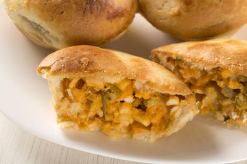 Empada Brazilian snack. pie with palm on white plate on wooden b