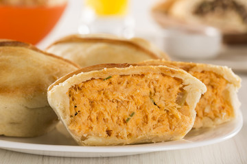 Empada Brazilian snack. pie with chicken on white plate on woode