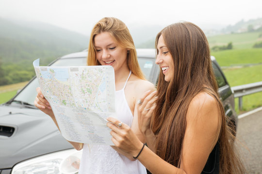Two girlfriends traveling and looking on map