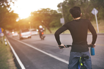 Cyclist riding a bike on an open road to the sunset