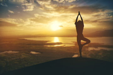 Silhouette young woman practicing yoga on sunset.