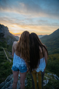 Two girlfriends looking forward on mountain sunset