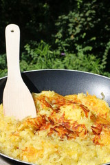 Sommerliches Kochen: Schweizer Rösti in einer Pfanne im Freien zubereiten
