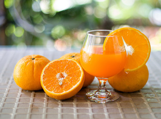 Fresh orange and orange juice in glass on tile table