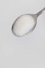 Fototapeta na wymiar white sugar in steel spoon on white background