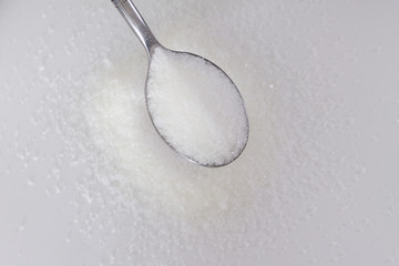 spoon of sugar on a background of scatter of sugar