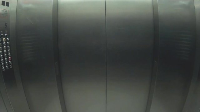 An elevator opens and closes its doors of steel