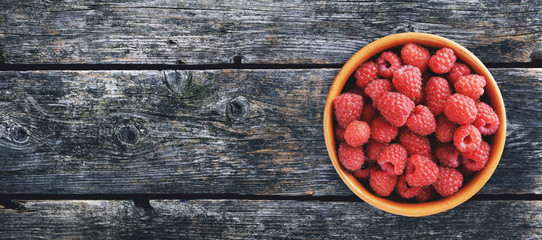Raspberries in a bowl on wooden background. Panorama. Banner. Menu.