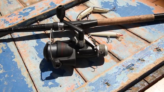A carbon fishing rod with lures over an old wood plank - zoom out