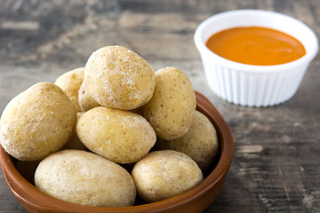 Canarian potatoes (papas arrugadas) with mojo sauce on wooden table

