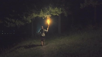 Brave girl traveling the night forest holding a fiery torch in hand. Slow motion.