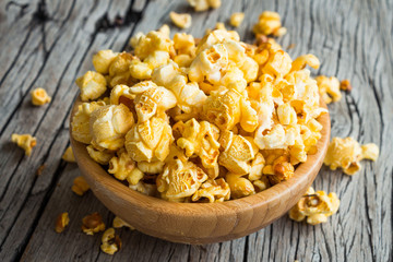 Popcorn in wooden bowl on wooden table background, selective focus, rustic style