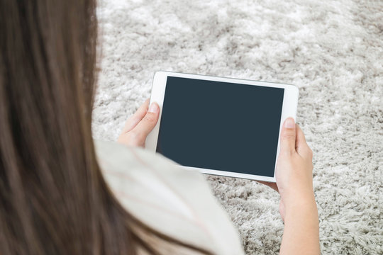 Closeup tablet computer on asian woman hand on blurred gray carpet floor textured background with copy space