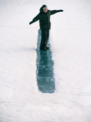 Toned image child to ride on an ice hill standing on their feet on snow background