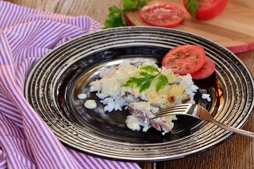 Meat under cheese with rice and tomatoes