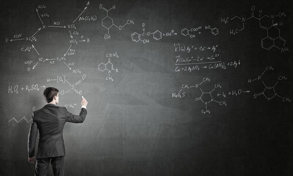 Scientist Writing Formulas On Chalkboard