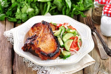 Grilled Pork chop with salad of tomatoes, cucumbers, onions, parsley and olive oil.