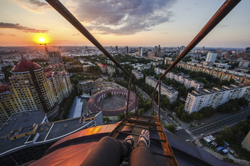 Fototapeta na wymiar Legs of man sititng on roof above street in center of Moscow at night