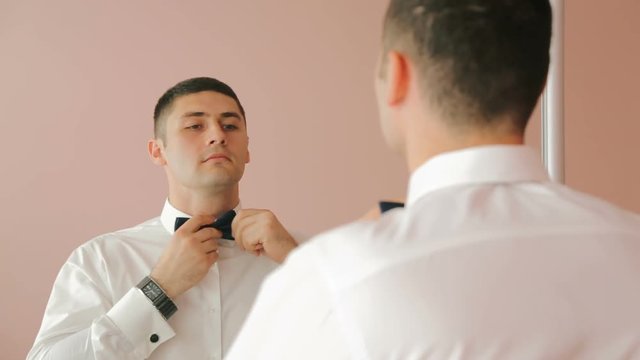 Man in white shirt tying a tie