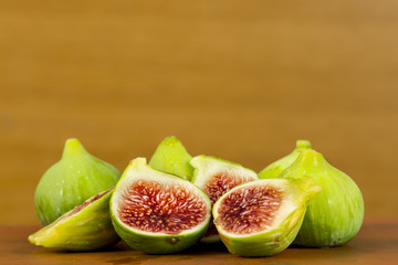 Fresh figs whith green skin and red flesh on brown wooden background