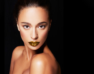 Beautiful woman with bronze skin, gold lipstick isolated on black background. Cosmetic makeup image. 