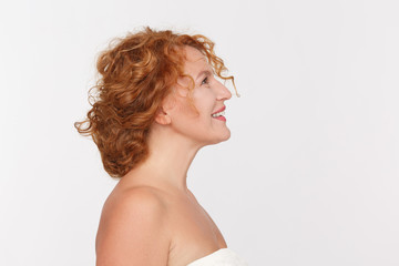 Closeup profile of happy mature woman smiling and looking upwards. Beautiful red haired lady posing isolated on white background in studio.
