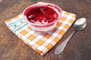 Parfait dessert with berries, milk souffle and jello layers. Treat in a glass on a rustic wooden background