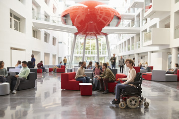 Student in wheelchair and colleagues in university lobby - obrazy, fototapety, plakaty