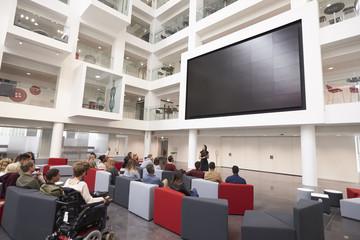 Students at a lecture in the atrium of a modern university