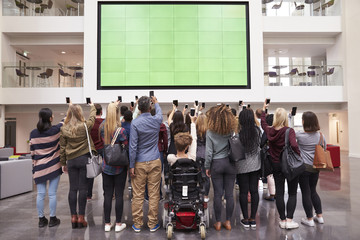 Students photograph screen with phones, back view full length